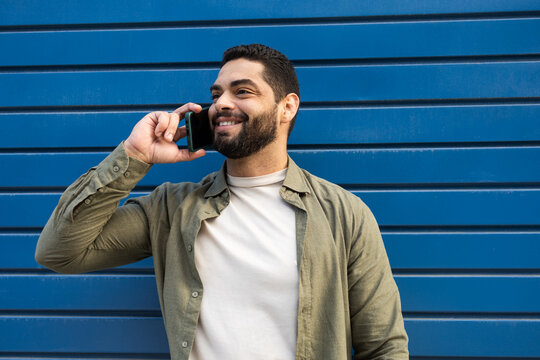 Man Enjoys Phone Call Against Blue Background in the City