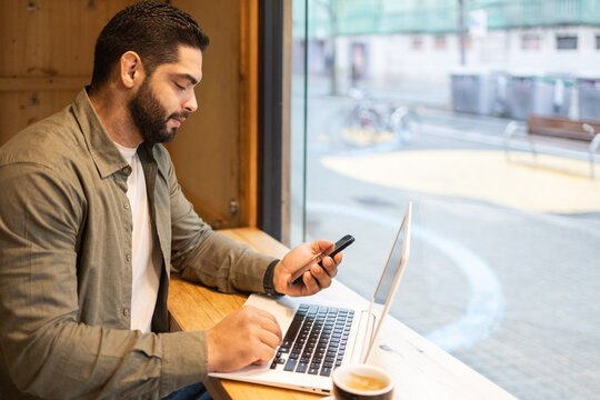 Businessman multitasking with laptop and phone in cafe of the city