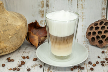 Latte macchiato in a glass cup with coffee beans on rustic wooden table

