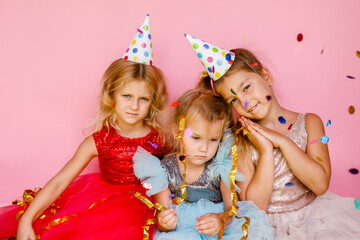 Three little girls at a party in elegant dresses with confetti