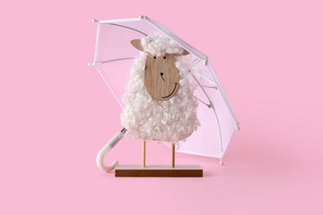 Creative composition with wooden toy sheep and mini umbrellas on pink background