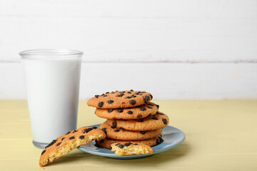 Tasty cookies with chocolate chips and glass of milk on table