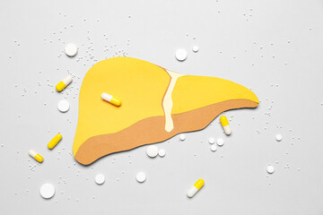 Yellow paper liver with pills on grey background