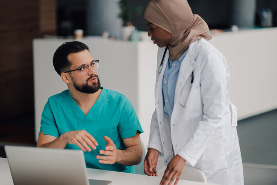 Doctors discussing patient data using laptop in hospital room