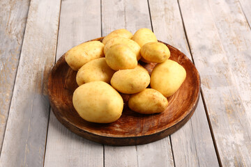 Plate with raw baby potatoes on grey wooden background