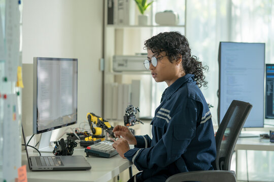  An Asian woman seamlessly integrates coding commands for robotic hands in a modern tech office, bridging creativity with automation and software engineering.