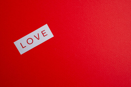 Paper with the word "love" written in red font on a red background. Love theme. Love message. Romantic love note on paper. Space for text