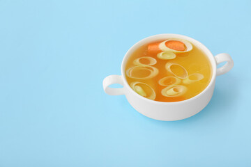 Pot of tasty vegetable broth on blue background