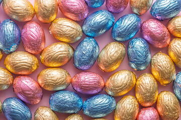 Obraz premium Chocolate easter eggs wrapped in multi colored foil. Top view.