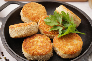 Frying pan with tasty meat cutlets on table