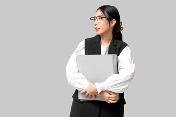 Portrait of young Asian businesswoman with office folders on grey background