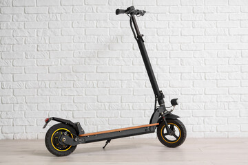 Modern electric kick scooter near white brick wall