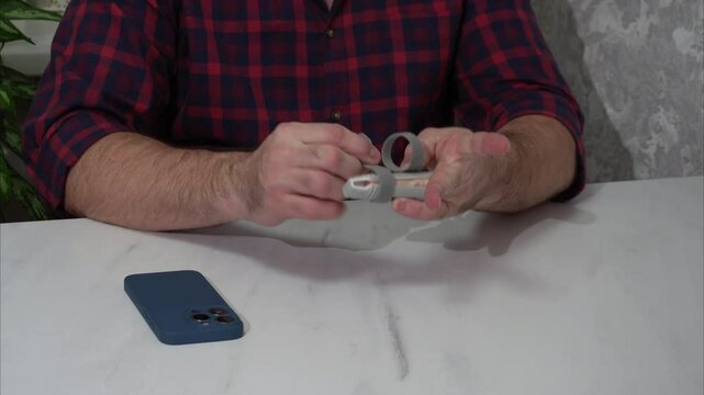 A man applies a medical brace to his finger for stabilization, orthopedic splint after injury