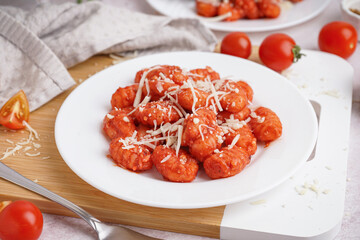 Plate of tasty gnocchi with cheese on white background
