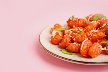 Plate of tasty gnocchi with cheese on pink background