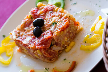 Timbale from tomatoes and canned tuna served with vegetables and herbs