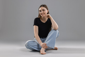Fototapeta premium Smiling woman in stylish jeans on grey background