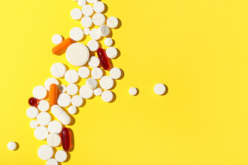 Composition with different pills on yellow background, closeup