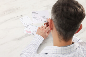 Obraz premium Paying bills. Man with different invoices at white marble table, above view