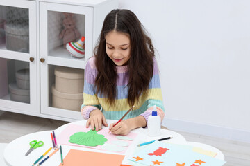 Girl drawing card at table indoors. Art and craft