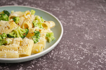 Plate of tasty pasta with broccoli on grey background
