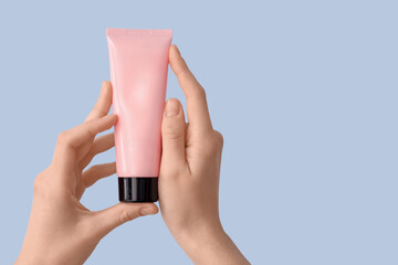 Female hands with tube of natural cream against color background, closeup