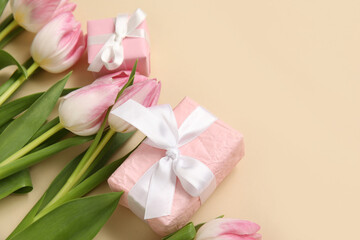 Pink tulips with gift boxes on beige background