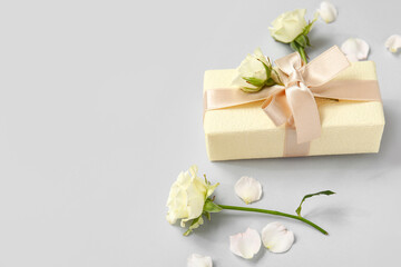 Gift box with roses and petals on white background