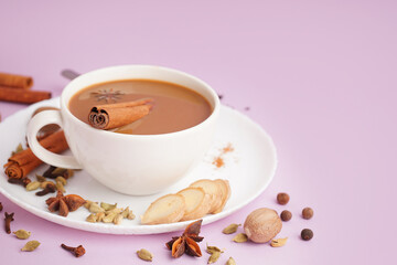 Cup of tasty masala tea with different spices on purple background, closeup