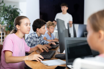 Portrait of teen schoolgirl sitting at table in computer class during lesson, smiling at camera. Concept of modern teenagers and technologies