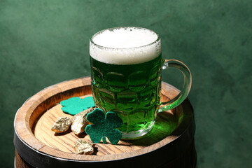 Glass of beer and clover on barrel against green background. St. Patrick's Day celebration