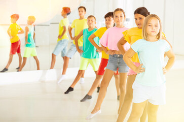 Focused positive tween girl with group of children standing in row one by one, learning classical...