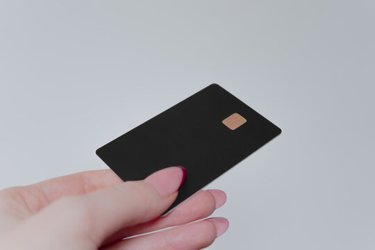 Capturing the essence of modern finance, a well-manicured hand presents a high-end black card, emphasizing luxury and security. The card's minimalist design suggests exclusivity and high status.