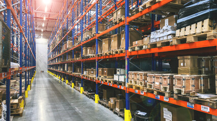 Baner. Wnętrze magazynu logistycznego, hala magazynowa, regały, paczki. Dystrybucja towarów, ładunek na paletach. Bez ludzi. © malgo_walko