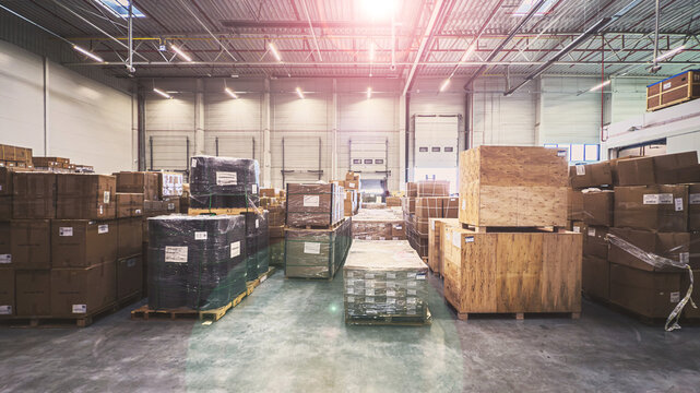 Baner. Wnętrze magazynu logistycznego, hala magazynowa, regały, paczki. Dystrybucja towar&oacute;w, ładunek na paletach. Bez ludzi.
