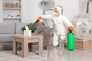 Male worker disinfecting sofa in room