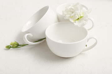Simple cups with flower on light background