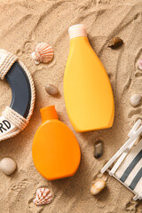 Bottles of sunscreen cream and lifebuoy ring on sand