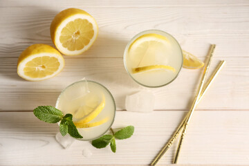 Glasses of fresh lemonade with mint and ice cubes on white wooden background