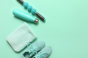 Sneakers, towel, sports water bottle and massager roller stick on turquoise background