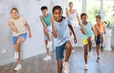 Positive boy exercising in group of classmates during dance class at school
