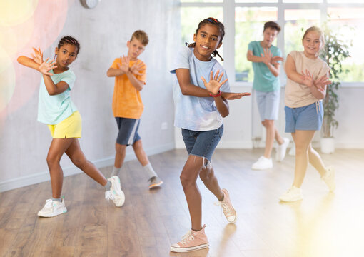 Positive cheerful smiling children studying modern style dance in class indoors