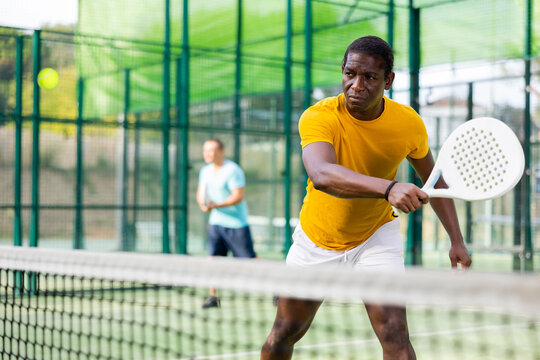 Sporty african american man playing padel tennis outdoor court