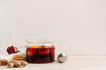 Glass cooking pot of hot mulled wine with orange and different spices on white background