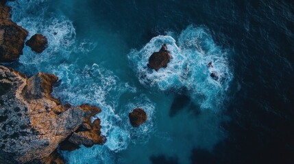 Aerial view of ocean waves crashing against rocky coastline landscape. Use to illustrate nature, travel, the power of the sea, or coastal themes.