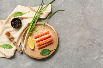 Wooden plate with tasty crab sticks, green onion, lemon and bowl of peppercorns on grey background © Pixel-Shot