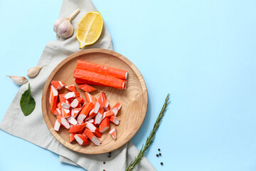 Wooden plate with tasty crab sticks and different spices on blue background © Pixel-Shot