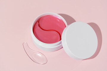 A white mock-up jar with pink hydrogel eye patches and a spatula on a pink background. Designed for deep hydration, wrinkle reduction, skin firming, and dark circle correction.