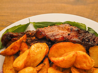 Simple meal with pork belly, potato wedges and pink coleslaw on white plate. Fine dinner with simple products.