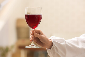 Female hand with glass of red wine at home